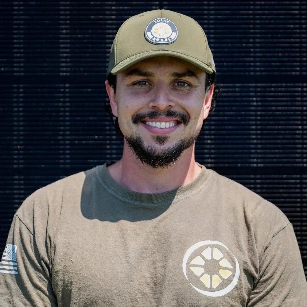 Cory Byrd, Owner and Field Operator at Solar Scapes, smiling in front of solar panels