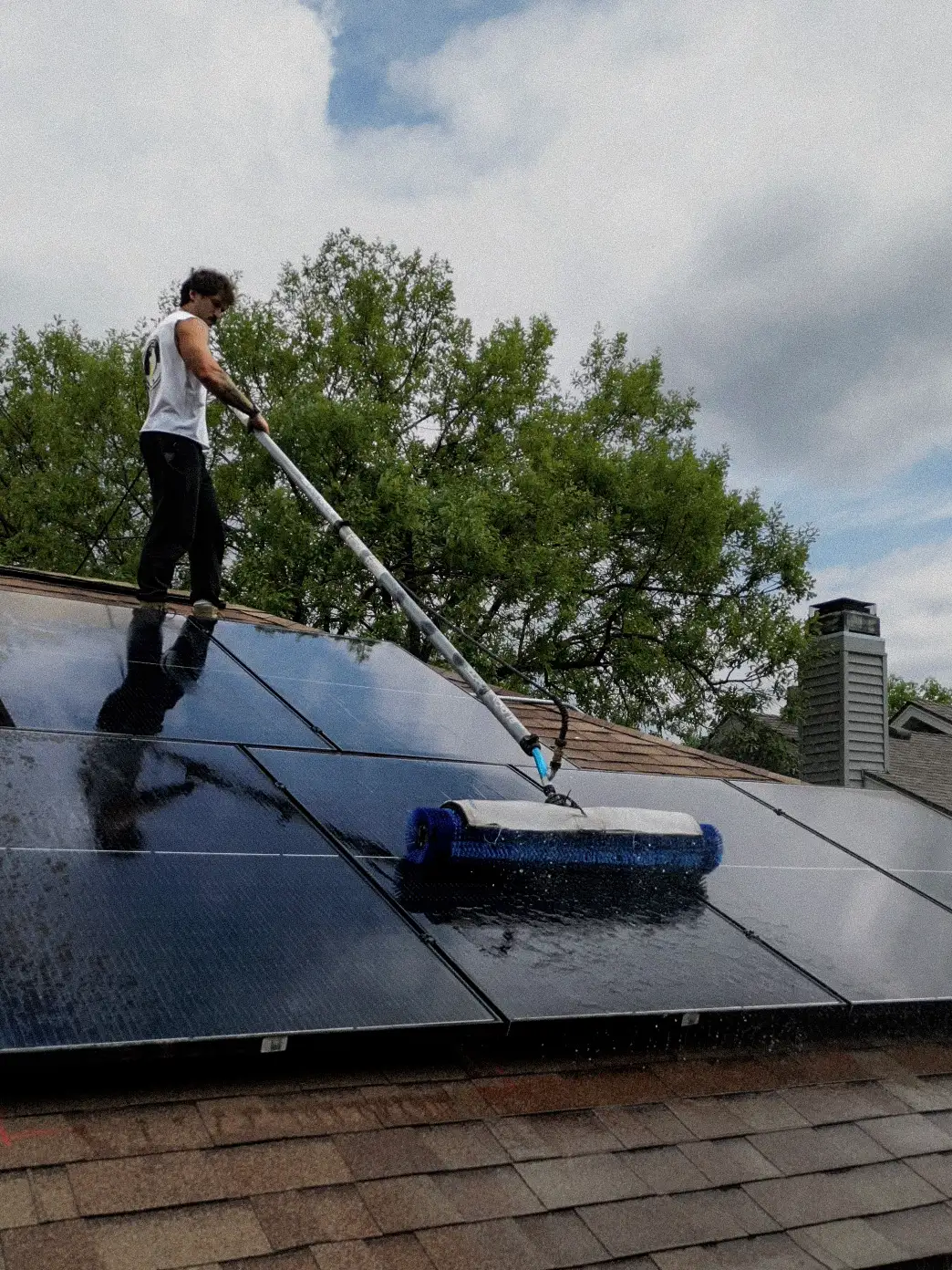 Solar Scapes technician cleaning residential rooftop solar panels
